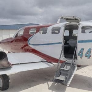 White jet parked on the tarmac in front of a hangar.