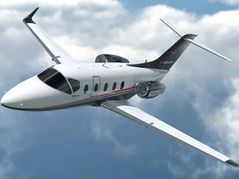 A light jet aircraft in flight against a cloudy sky.