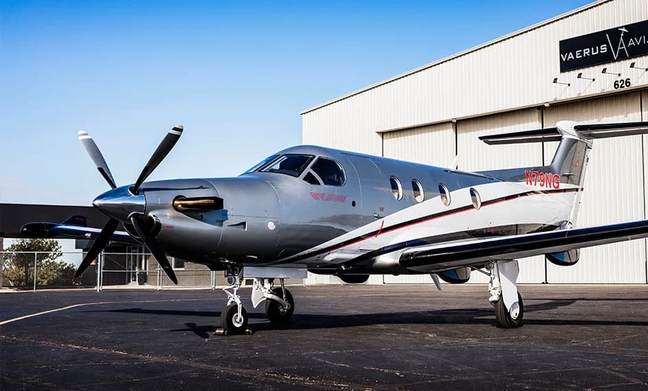 A Pilatus PC-12, registration N79NG, sits on the tarmac in front of a hangar.